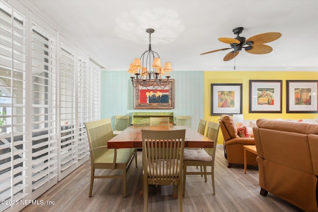 dining area featuring crown molding, ceiling fan with notable chandelier, wood finished floors, and a healthy amount of sunlight
