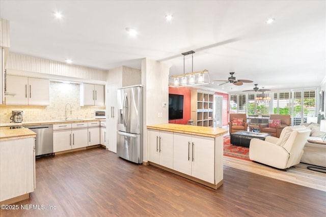 kitchen featuring light countertops, dark wood finished floors, stainless steel appliances, a ceiling fan, and a peninsula