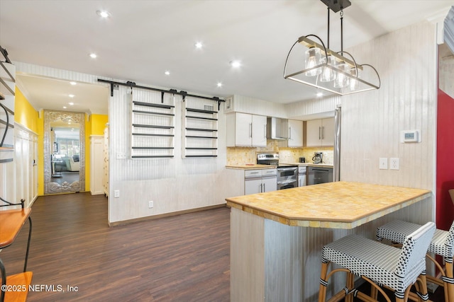 kitchen with wall chimney range hood, a barn door, light countertops, dark wood finished floors, and range with two ovens
