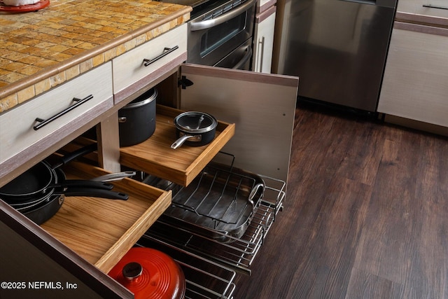 interior space with tile countertops, dark wood-style flooring, and appliances with stainless steel finishes