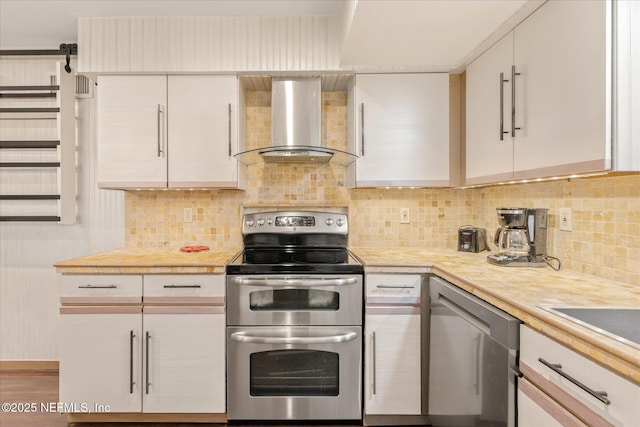 kitchen featuring light countertops, wall chimney exhaust hood, decorative backsplash, and stainless steel appliances