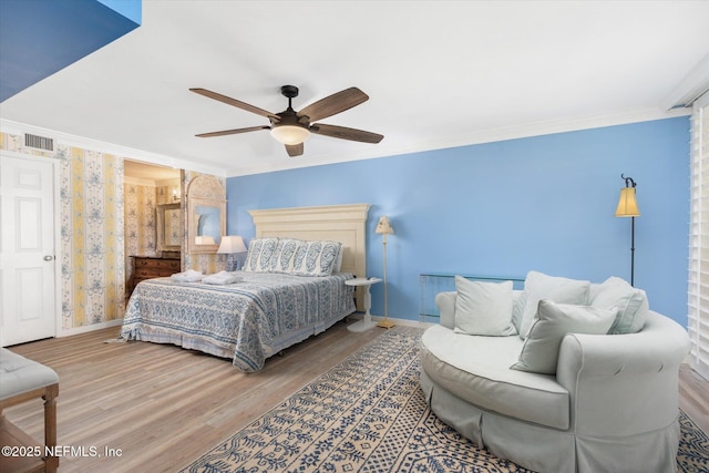 bedroom with ceiling fan, baseboards, wood finished floors, visible vents, and ornamental molding