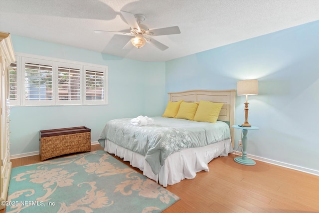 bedroom with a textured ceiling, baseboards, a ceiling fan, and wood finished floors
