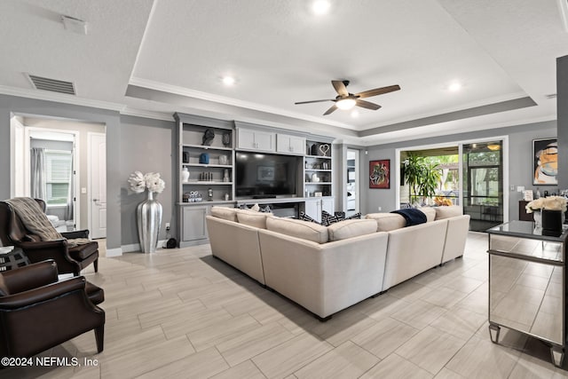 living area featuring a ceiling fan, visible vents, a raised ceiling, and crown molding