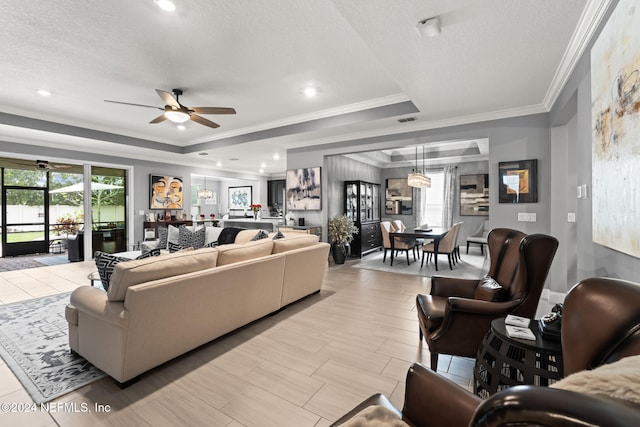 living area with a textured ceiling, ceiling fan, and crown molding