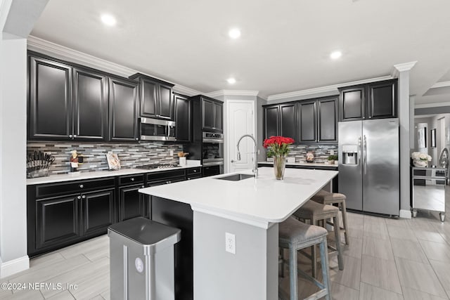 kitchen with dark cabinets, a kitchen breakfast bar, an island with sink, and appliances with stainless steel finishes