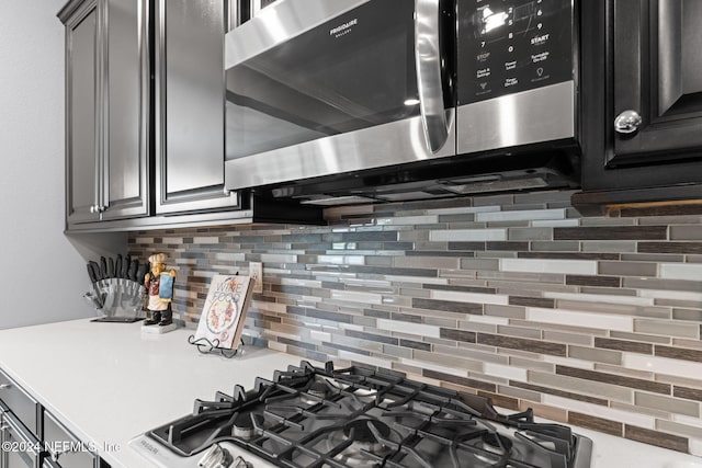 kitchen featuring backsplash, light countertops, appliances with stainless steel finishes, and dark cabinetry