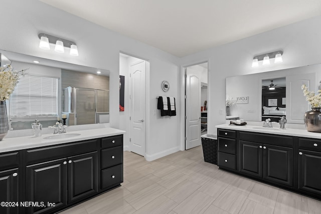 ensuite bathroom with two vanities, a shower stall, ceiling fan, and a sink