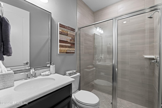 bathroom with a shower stall, toilet, and vanity