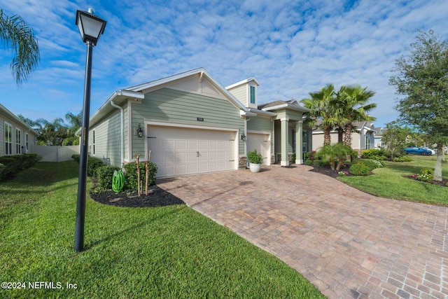 single story home with an attached garage, a front lawn, fence, and decorative driveway