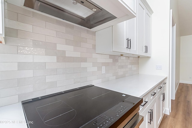 6388 Miltondale Rd, Macclenny, FL 32063 - kitchen with light countertops, black electric cooktop, white cabinetry, and custom range hood