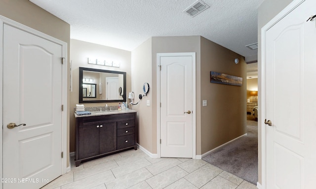 bathroom featuring a textured ceiling, baseboards, visible vents, and vanity