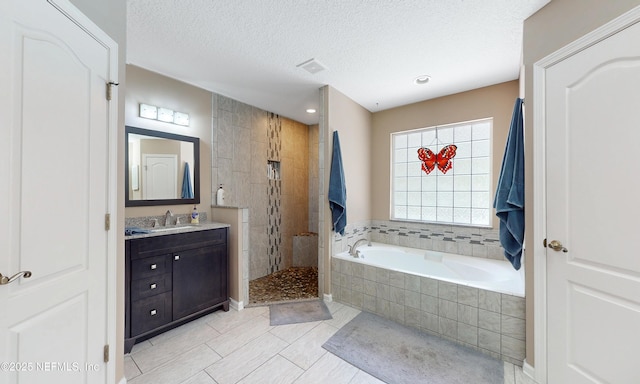 bathroom with vanity, tile patterned flooring, walk in shower, a textured ceiling, and a bath
