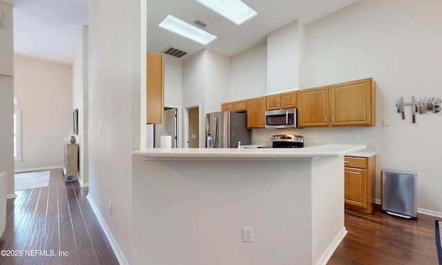 kitchen with visible vents, appliances with stainless steel finishes, dark wood finished floors, light countertops, and high vaulted ceiling
