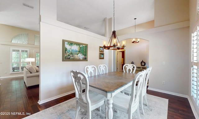 dining space featuring dark wood-type flooring, a chandelier, and high vaulted ceiling