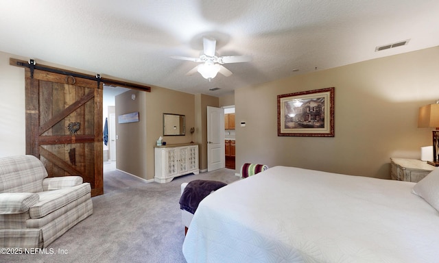 bedroom with ceiling fan, a barn door, light carpet, a textured ceiling, and visible vents
