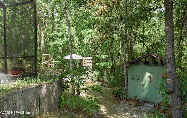 exterior space with a storage unit, an outbuilding, and a forest view
