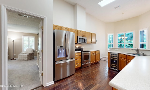 kitchen featuring wine cooler, a high ceiling, light countertops, a sink, and stainless steel appliances