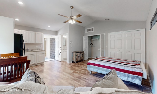 bedroom featuring visible vents, freestanding refrigerator, two closets, baseboards, and light wood-style flooring
