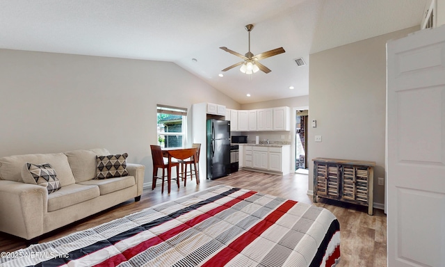 living room featuring ceiling fan, recessed lighting, vaulted ceiling, light wood-type flooring, and visible vents