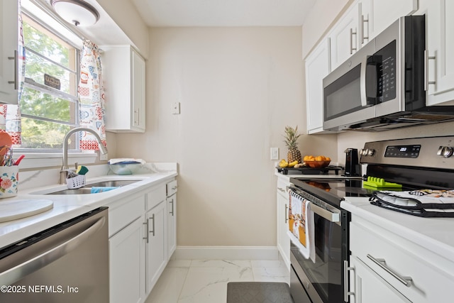 4532 Jade Dr E, Jacksonville, FL 32210 - kitchen featuring marble finish floor, appliances with stainless steel finishes, a sink, and white cabinets