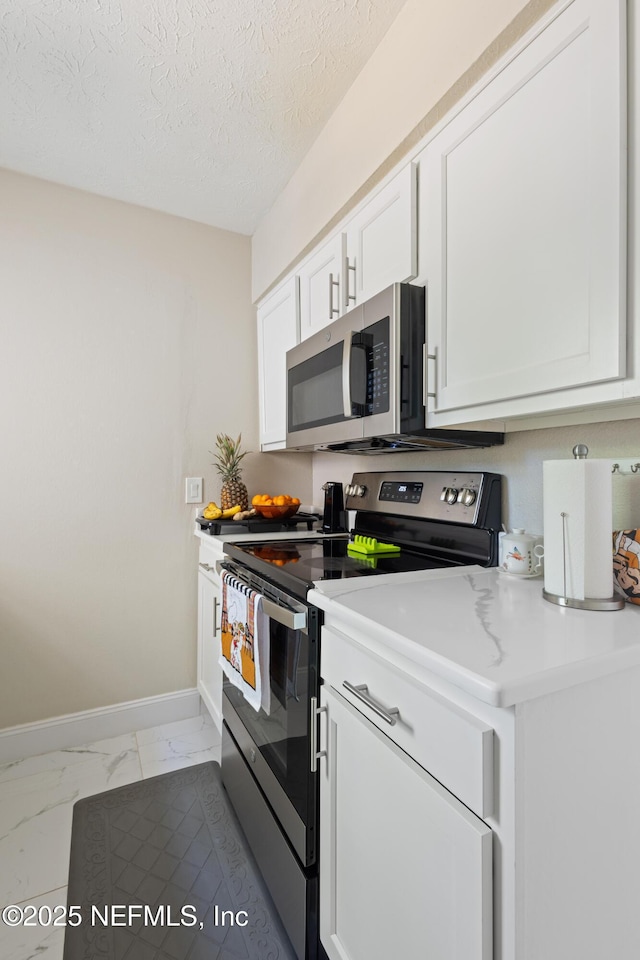 4532 Jade Dr E, Jacksonville, FL 32210 - kitchen with white cabinets, marble finish floor, stainless steel appliances, light countertops, and a textured ceiling