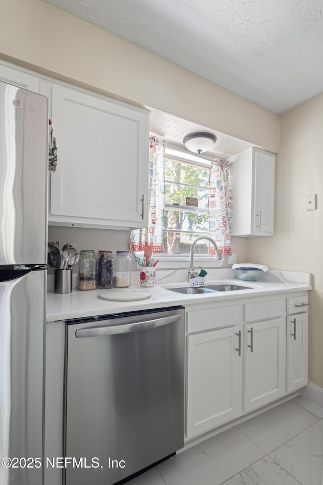 4532 Jade Dr E, Jacksonville, FL 32210 - kitchen featuring a sink, marble finish floor, stainless steel appliances, light countertops, and white cabinets