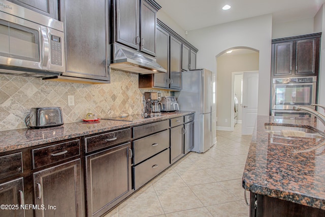 1911 Salt Creek Dr, Fleming Island, FL 32003 - kitchen featuring stainless steel appliances, arched walkways, a sink, dark stone countertops, and under cabinet range hood