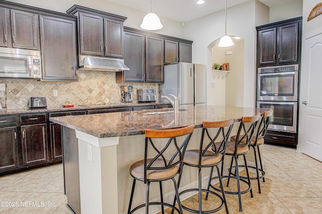 1911 Salt Creek Dr, Fleming Island, FL 32003 - kitchen with stainless steel appliances, a sink, tasteful backsplash, light tile patterned flooring, and under cabinet range hood