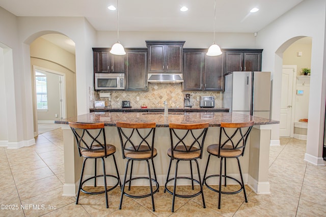 1911 Salt Creek Dr, Fleming Island, FL 32003 - kitchen featuring under cabinet range hood, freestanding refrigerator, stainless steel microwave, and a breakfast bar area
