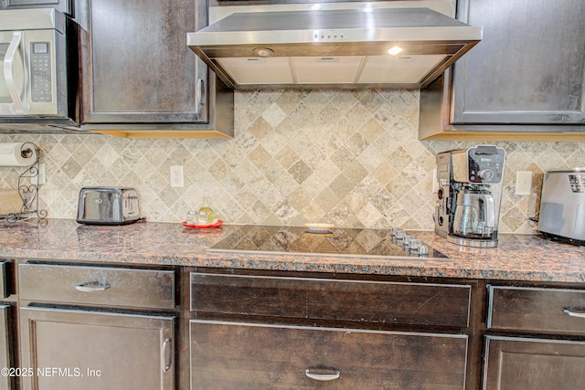 1911 Salt Creek Dr, Fleming Island, FL 32003 - kitchen with black electric cooktop, stainless steel microwave, dark brown cabinetry, decorative backsplash, and wall chimney range hood