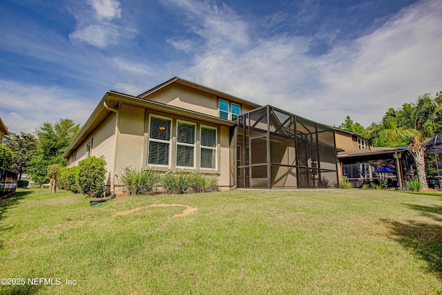 1911 Salt Creek Dr, Fleming Island, FL 32003 - back of house featuring glass enclosure, a lawn, and stucco siding
