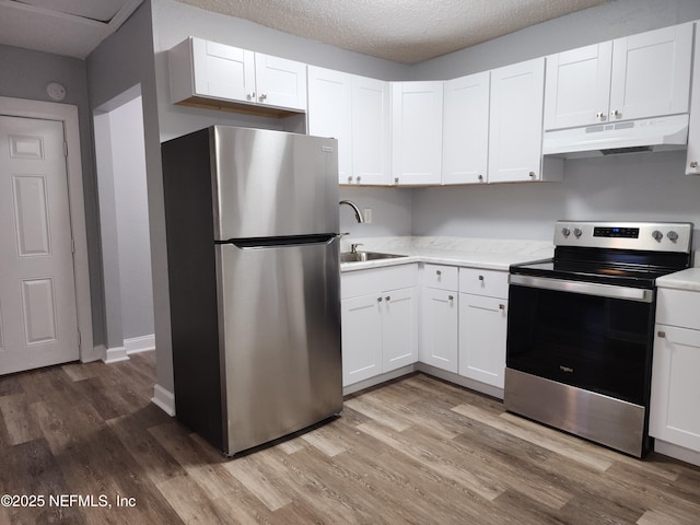 860 Westbrook Rd, Jacksonville, FL 32209 - kitchen featuring light wood-style floors, white cabinetry, appliances with stainless steel finishes, under cabinet range hood, and a sink