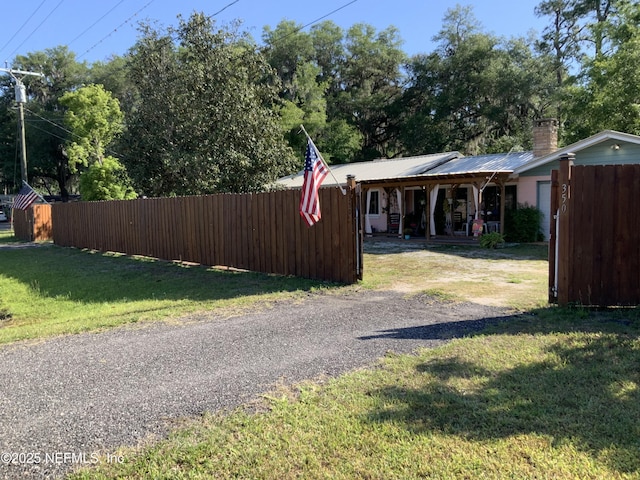 exterior space featuring fence, a lawn, driveway, and a chimney
