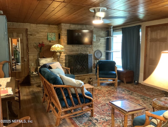 interior space featuring wood ceiling, a ceiling fan, a stone fireplace, and wood finished floors