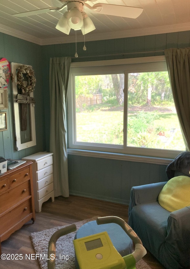 living area featuring wood finished floors, crown molding, and a ceiling fan