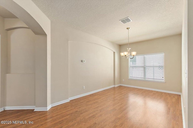13644 Goodson Pl, Jacksonville, FL 32226 - empty room with arched walkways, wood finished floors, and a textured ceiling