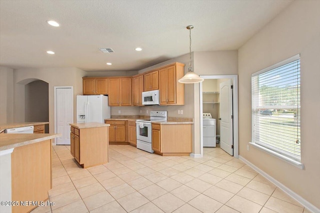 13644 Goodson Pl, Jacksonville, FL 32226 - kitchen featuring a center island, white appliances, arched walkways, washer / dryer, and light countertops