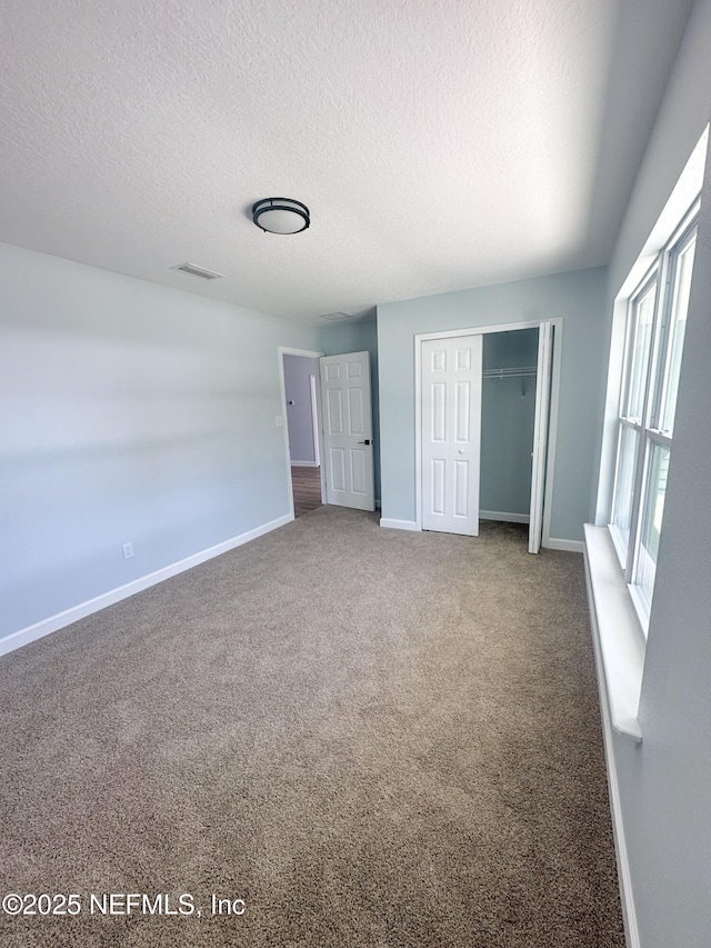 112 Moseley Ave, Palatka, FL 32177 - unfurnished bedroom with a textured ceiling, a closet, baseboards, and carpet floors