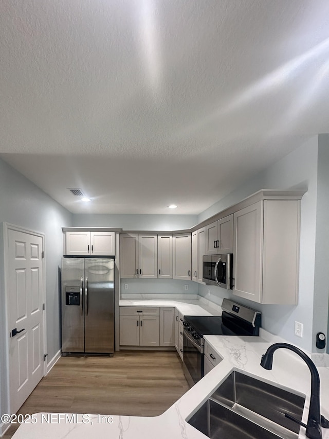 112 Moseley Ave, Palatka, FL 32177 - kitchen featuring appliances with stainless steel finishes, a sink, light wood-style flooring, a textured ceiling, and gray cabinetry