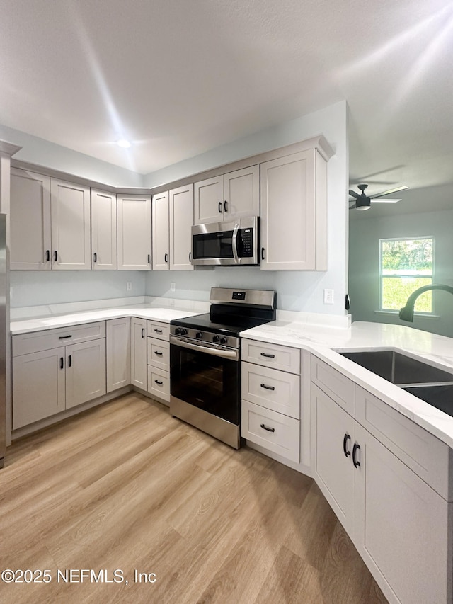 112 Moseley Ave, Palatka, FL 32177 - kitchen featuring appliances with stainless steel finishes, a sink, light countertops, light wood-style floors, and ceiling fan