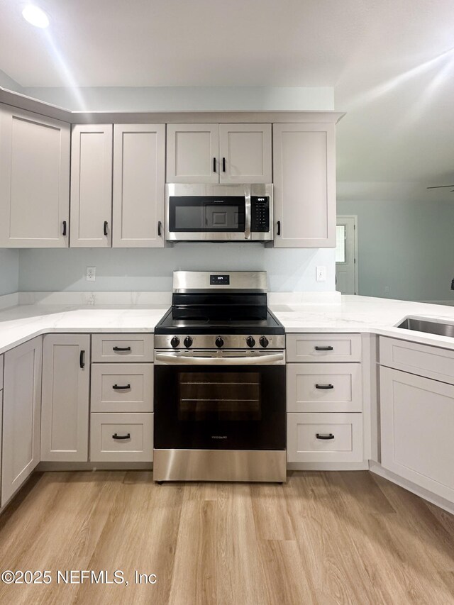112 Moseley Ave, Palatka, FL 32177 - kitchen with stainless steel appliances, a sink, light wood-type flooring, and light stone counters