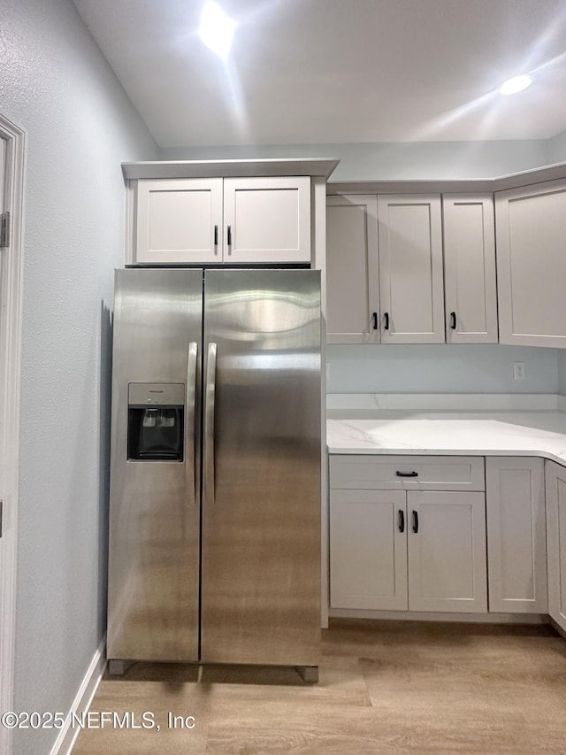 112 Moseley Ave, Palatka, FL 32177 - kitchen featuring stainless steel fridge with ice dispenser, light wood finished floors, light countertops, baseboards, and gray cabinets