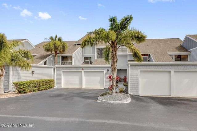 view of front of home with roof with shingles and driveway