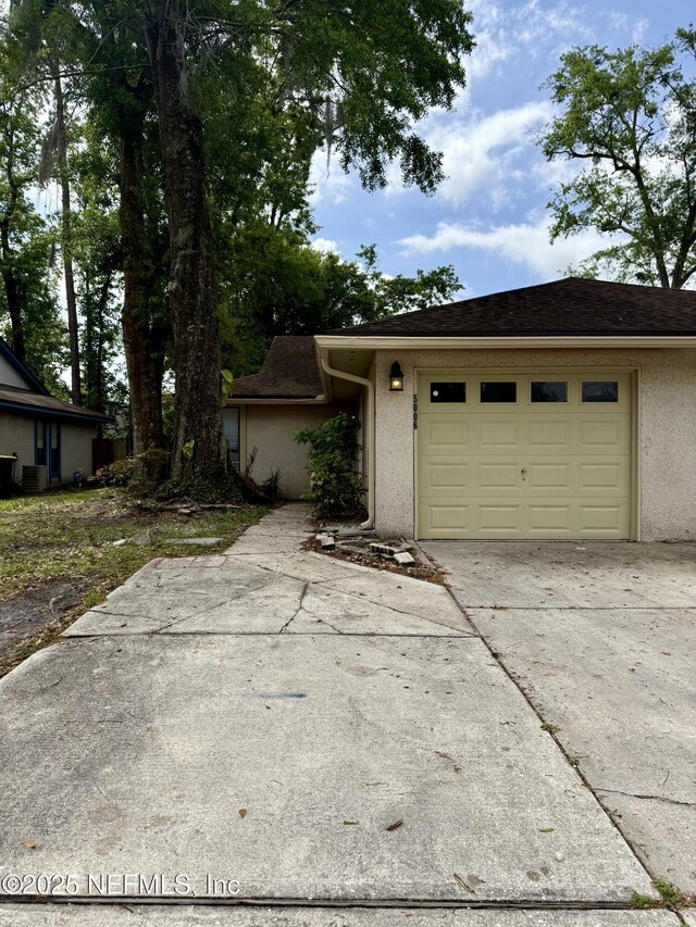 5006 Knightsbridge Cir N, Jacksonville, FL 32244 - view of front facade featuring stucco siding, an attached garage, roof with shingles, and concrete driveway