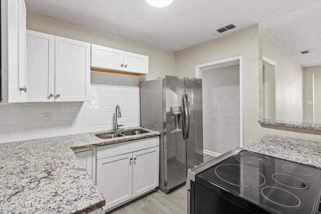 5741 Castellano Ave, Jacksonville, FL 32208 - kitchen with a sink, stainless steel fridge with ice dispenser, black electric range oven, white cabinets, and light stone counters