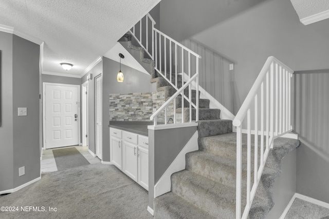 stairs with crown molding, baseboards, carpet flooring, and a textured ceiling