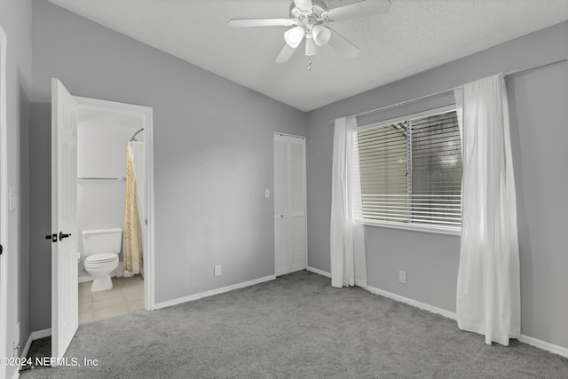 unfurnished bedroom with a closet, baseboards, a textured ceiling, connected bathroom, and carpet