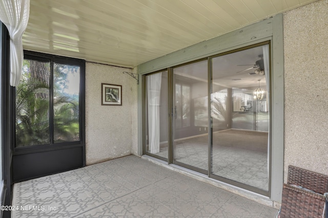 unfurnished sunroom featuring wood ceiling and a ceiling fan