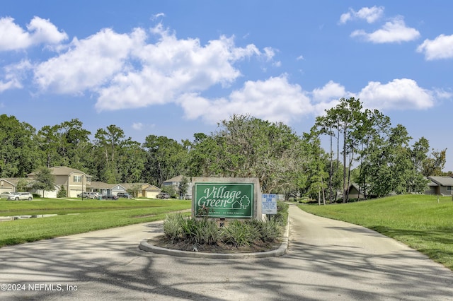 community / neighborhood sign with concrete driveway, a yard, and a residential view
